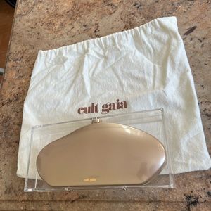 Cult Gaia "Annika" metallic acrylic clutch bag with transparent cover.